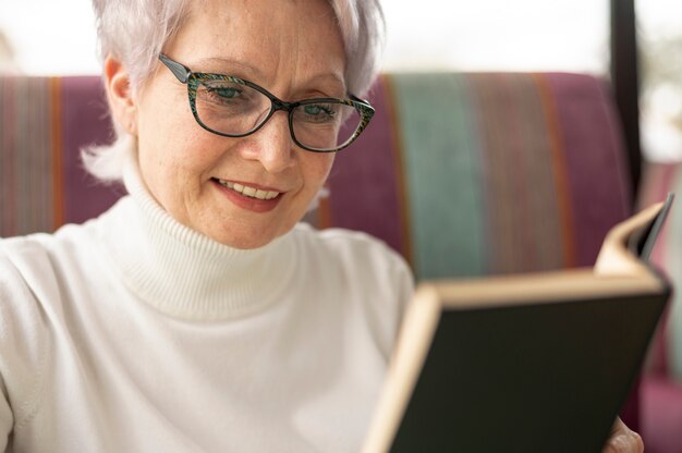 Close-up senior femenino en restaurante leyendo