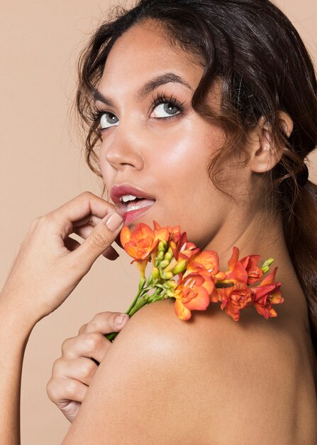 Close-up shot mujer sosteniendo flores vibrantes sobre el hombro