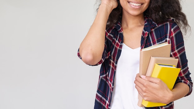 Foto gratuita close-up smiley adolescente con pila de libros