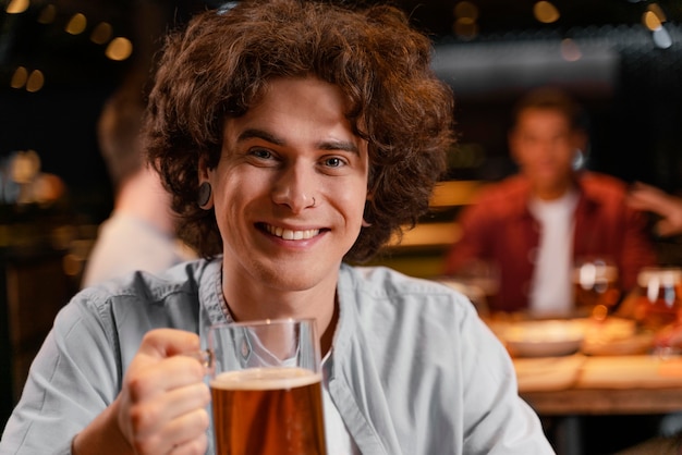 Close-up sonriente hombre sosteniendo jarra de cerveza en el pub