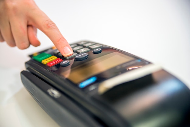 Close-up de las tarjetas de servicio con POS-terminal, aislado en fondo blanco. Manos de mano con tarjeta de crédito y terminal bancario