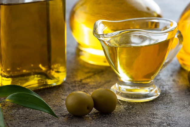 Close-up taza de aceite de oliva y aceitunas verdes