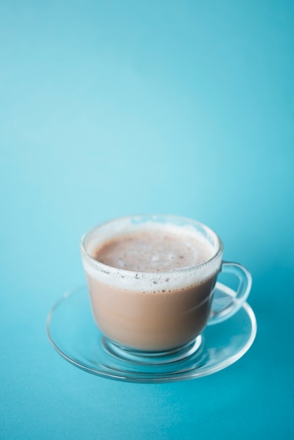 Close-up taza de café con leche con fondo azul.