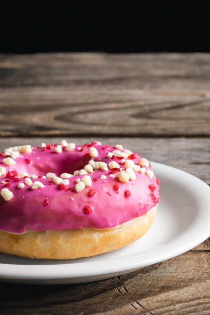 Closeup apetitoso donut rosa sobre un fondo de madera