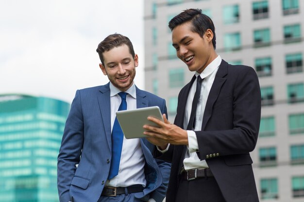 Closeup de compañeros de trabajo sonriendo utilizando Tablet al aire libre