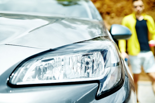 Closeup faros de coche gris con hombre