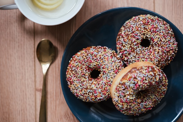 Closeup foto de deliciosas donas espolvoreadas sobre una superficie de madera y una cuchara en el lateral