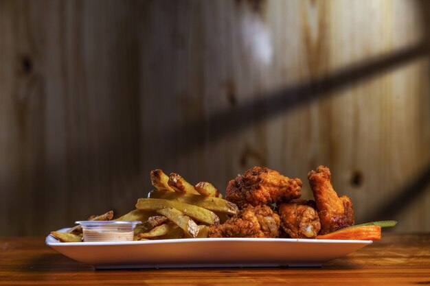 Closeup foto de deliciosas piernas de pollo con especias con papas fritas en la mesa