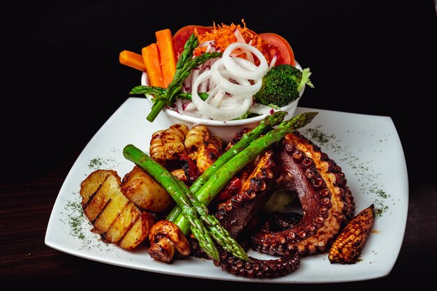 Closeup foto de un delicioso plato de pulpo asado con espárragos asados y verduras