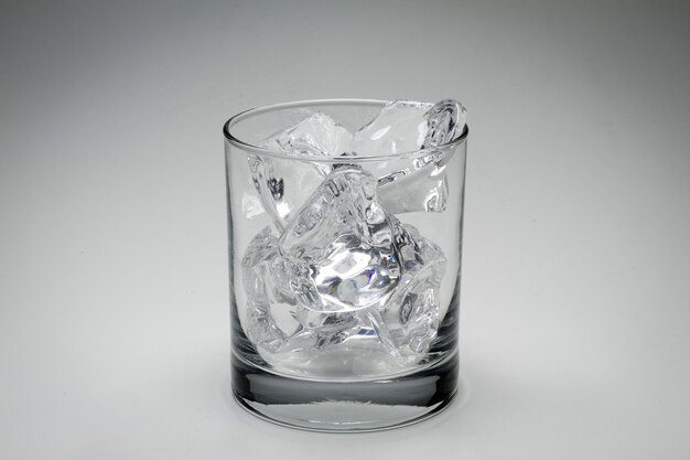 Closeup foto de escala de grises de un vaso lleno de cubitos de hielo aislado