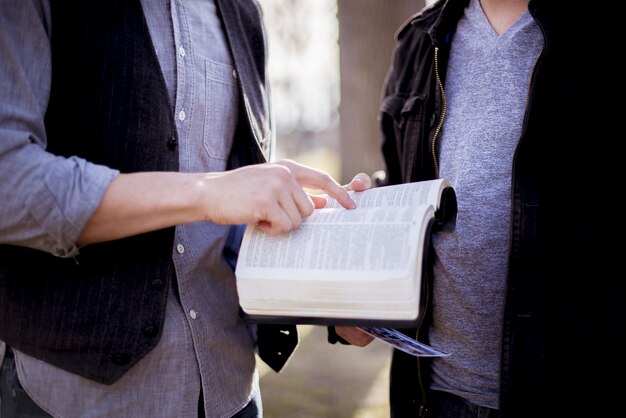 Closeup foto de un hombre apuntando a una oración en la Biblia