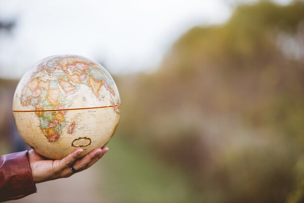 Closeup foto de un hombre sosteniendo un globo de escritorio con un fondo borroso