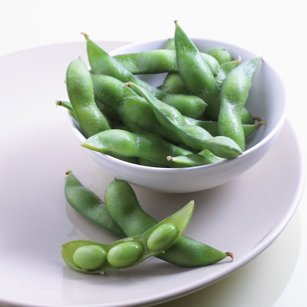 Closeup foto de judías verdes frescas en un recipiente blanco y plato sobre la mesa