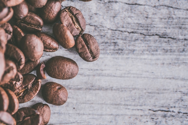 Closeup foto de un montón de semillas de café sobre un fondo de madera gris