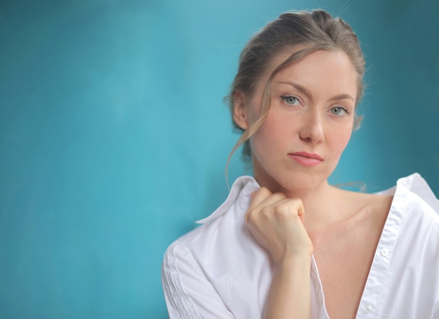 Closeup foto de mujer bonita con camisa blanca aislada en azul