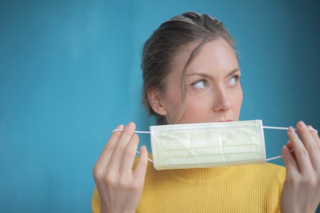 Closeup foto de mujer bonita con tapa amarilla poniendo mascarilla médica