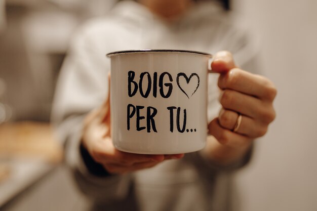 Closeup foto de una mujer sosteniendo una taza de cerámica blanca con letras de canciones impresas