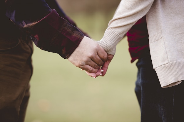 Closeup foto de una pareja tomados de la mano con un fondo borroso