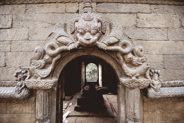 Closeup foto de una puerta arqueada con escultura en un templo hindú en Nepal