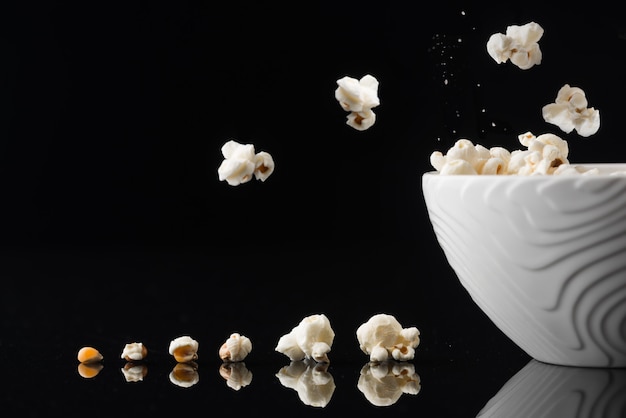 Closeup foto de un tazón blanco con palomitas de maíz sobre un fondo oscuro