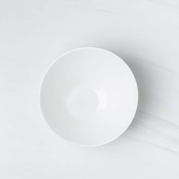 Closeup foto de un tazón de cerámica blanco vacío en una pared blanca