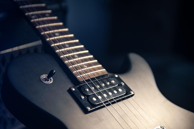Closeup guitarra eléctrica negra sobre un fondo oscuro