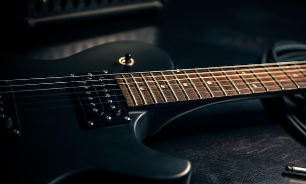 Closeup guitarra eléctrica negra sobre un fondo oscuro