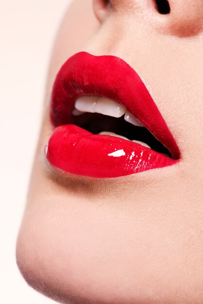 Closeup hermosos labios femeninos con lápiz labial rojo. Maquillaje de brillo brillante de moda glamour.