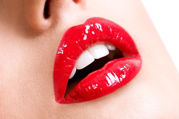 Closeup hermosos labios femeninos con lápiz labial rojo. Maquillaje de brillo brillante de moda glamour.