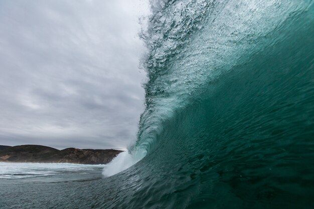 Closeup imagen de las olas del mar con montañas bajo un cielo nublado en Portugal