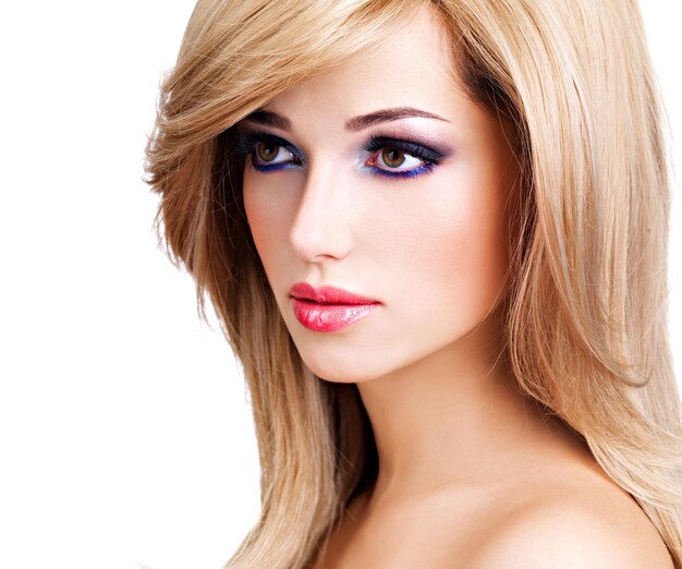 Closeup retrato de una bella mujer joven con largos pelos blancos. Modelo de moda posando sobre pared blanca