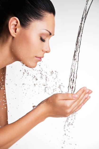 Closeup retrato de una bella mujer lavándose la cara limpia con agua