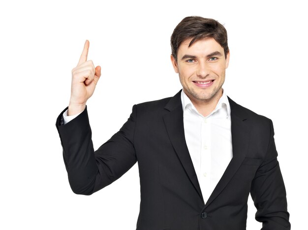 Closeup retrato del feliz hombre de negocios apunta con su dedo hacia arriba en traje negro aislado en blanco