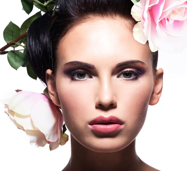 Closeup retrato de hermosa mujer joven con flores rosas en el pelo - aislado en blanco