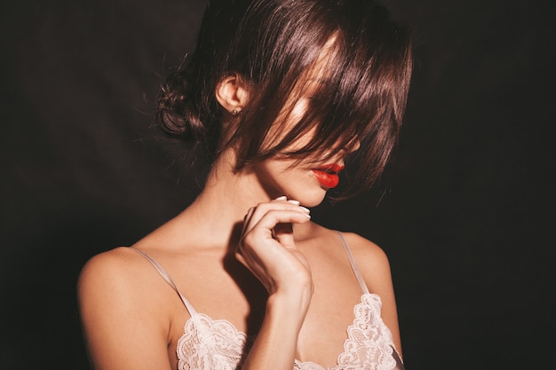 Closeup retrato de hermosa mujer morena sensual. Chica en ropa clásica beige elegante. Modelo con labios rojos aislado en negro