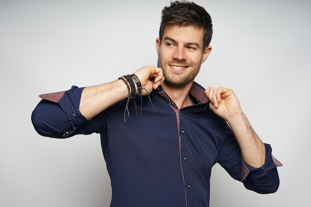 Foto gratuita closeup retrato de hombre sonriente sosteniendo con confianza su cuello y aislado sobre la pared blanca