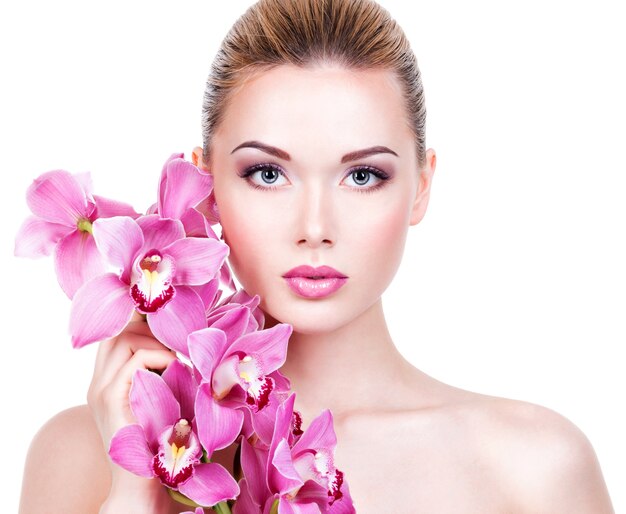 Closeup retrato de joven bella mujer con una piel limpia y sana de la cara. Chica bastante adulta con flor cerca de la cara. - aislado en fondo blanco