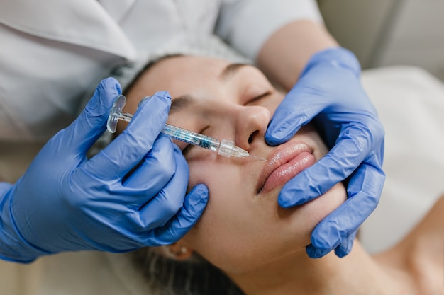 Foto gratuita closeup retrato joven haciendo procedimientos de botox por profesional. inyección, elaboración de labios, dispositivos modernos, tecnología, medicina, terapia de cosmetología