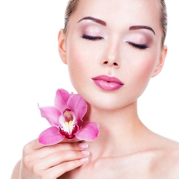 Foto gratuita closeup retrato de joven hermosa con flor cerca de la cara - aislada sobre fondo blanco