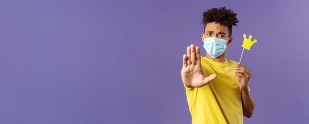 Closeup retrato de joven hipster chico en máscara médica estirar la mano adelante parada gesto sosteniendo smal