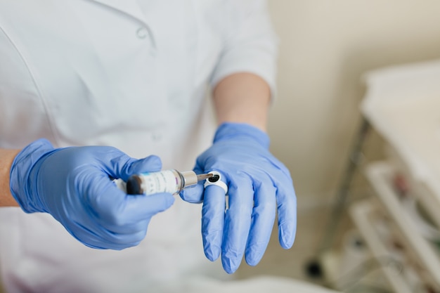 Closeup retrato de manos del doctor en guantes azules trabajando con medicene. Preparación profesional de cosmetología, procedimientos dermatológicos, lifting, rejuvenecimiento, gotas, asistencia sanitaria, hospitalaria, terapéutica.