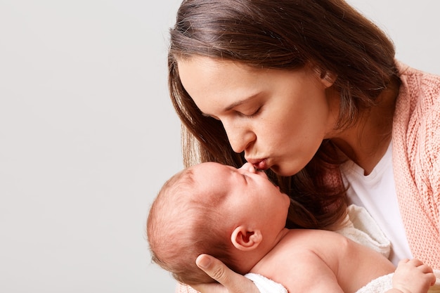 Foto gratuita closeup retrato de mujer encantadora besando a su bebé recién nacido con los ojos cerrados