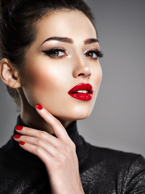 Closeup retrato de mujer hermosa con maquillaje brillante y uñas rojas. Chica adulta joven sexy con lápiz labial rojo.