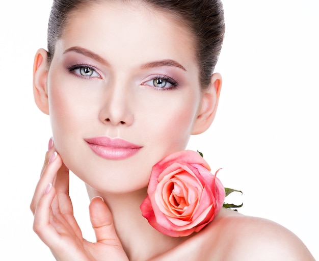 Foto gratuita closeup retrato de mujer joven hermosa con piel sana y flor cerca de la cara - aislado en blanco.