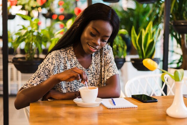 Closeup retrato de mujer negra joven feliz tomando café en la cafetería