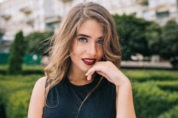 Closeup retrato de niña bonita con maquillaje atractivo y labios rojos en la calle