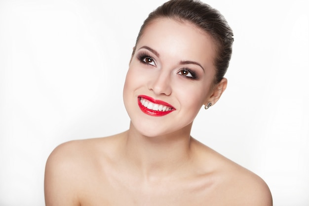 Closeup retrato de sexy modelo caucásico joven sonriente con glamour labios rojos, maquillaje brillante, maquillaje flecha, tez de pureza. Perfecta piel limpia dientes blancos