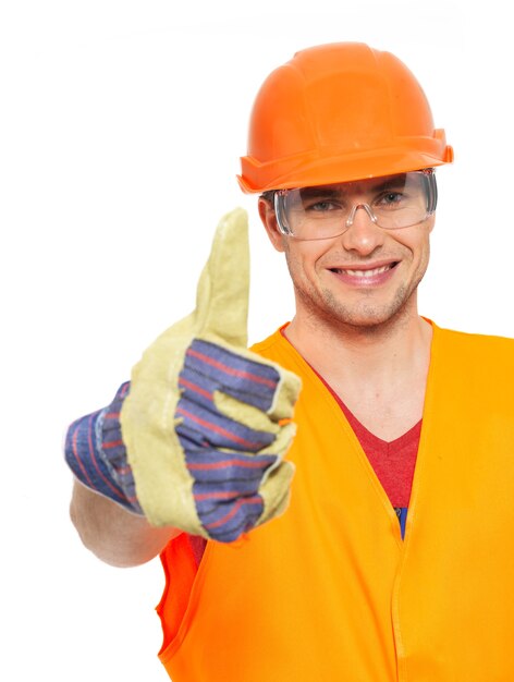 Closeup retrato de sonriente artesano Thumbs up firmar en uniforme protector naranja aislado en la pared blanca