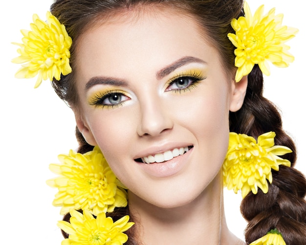 Closeup rostro de una joven hermosa mujer sonriente con maquillaje amarillo brillante Retrato de moda Chica atractiva con coletas de peinado con estilo aislado en blanco Maquillaje profesional