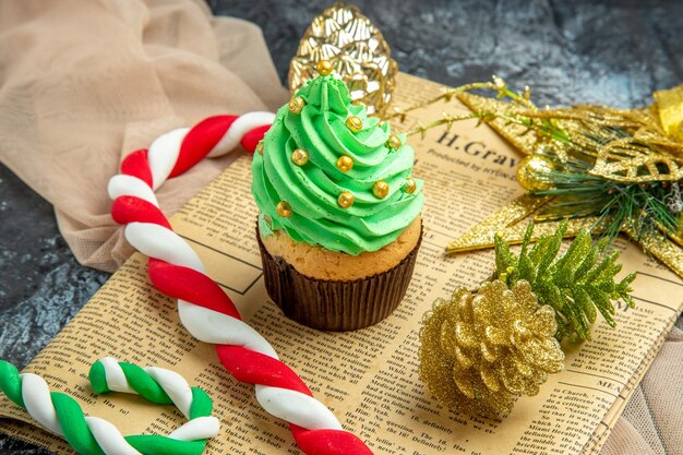 Foto gratuita closeup vista inferior mini cupcake dulces de navidad adornos de navidad en el periódico mantón beige sobre fondo oscuro